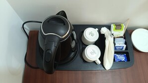 Une machine à café, deux tasses blanches, un mouchoir et une boîte de mouchoirs sur un plateau en bois.