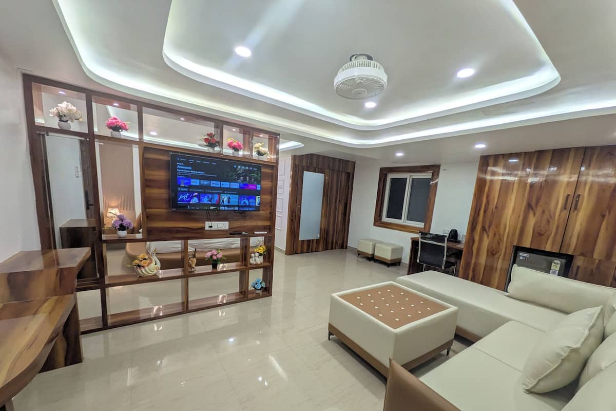Uma sala de estar moderna com uma TV de tela plana, estantes de madeira com objetos decorativos, um sofá e uma mesa de centro.