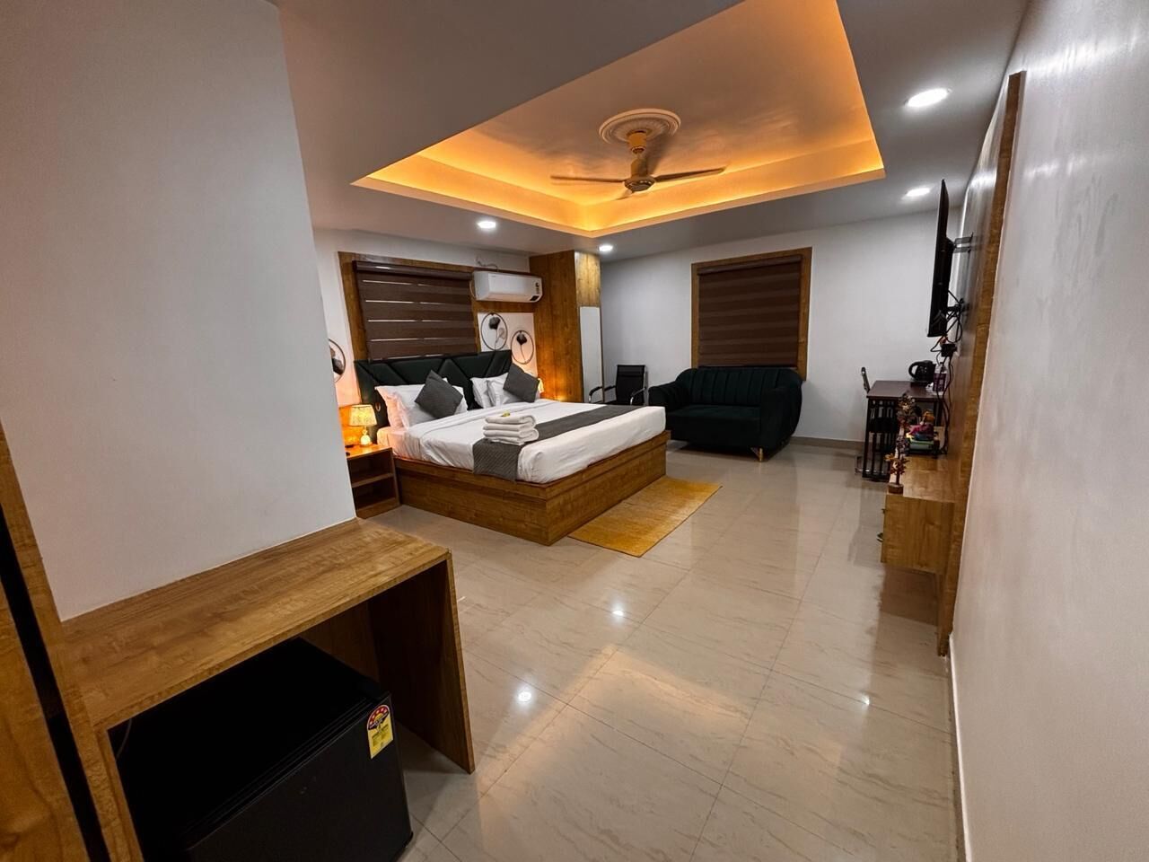 A modern bedroom with a wooden bed, bedside tables, a desk, and a ceiling fan.