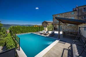 A swimming pool with lounge chairs, a stone building, and a view of the landscape. - Casa Chiara, Your Holiday Home with pool in Motovun, Istria (Motovun)