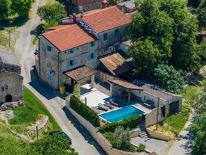 A stone building with a red-tiled roof, a swimming pool, and a small patio area. - Casa Chiara, Your Holiday Home with pool in Motovun, Istria (Motovun)