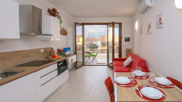 Eine moderne Küche mit Essbereich, einem roten Sofa und Blick nach außen.