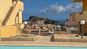 Ein Schwimmbad mit Blick auf eine Küstenstadt und eine Burg im Hintergrund.