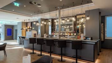 Un bar moderno con varios taburetes, una barra con menú y lámparas colgantes.