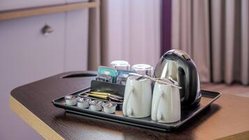 Una bandeja con tetera, tazas y sobre de té sobre una mesa de madera en una habitación de hotel.