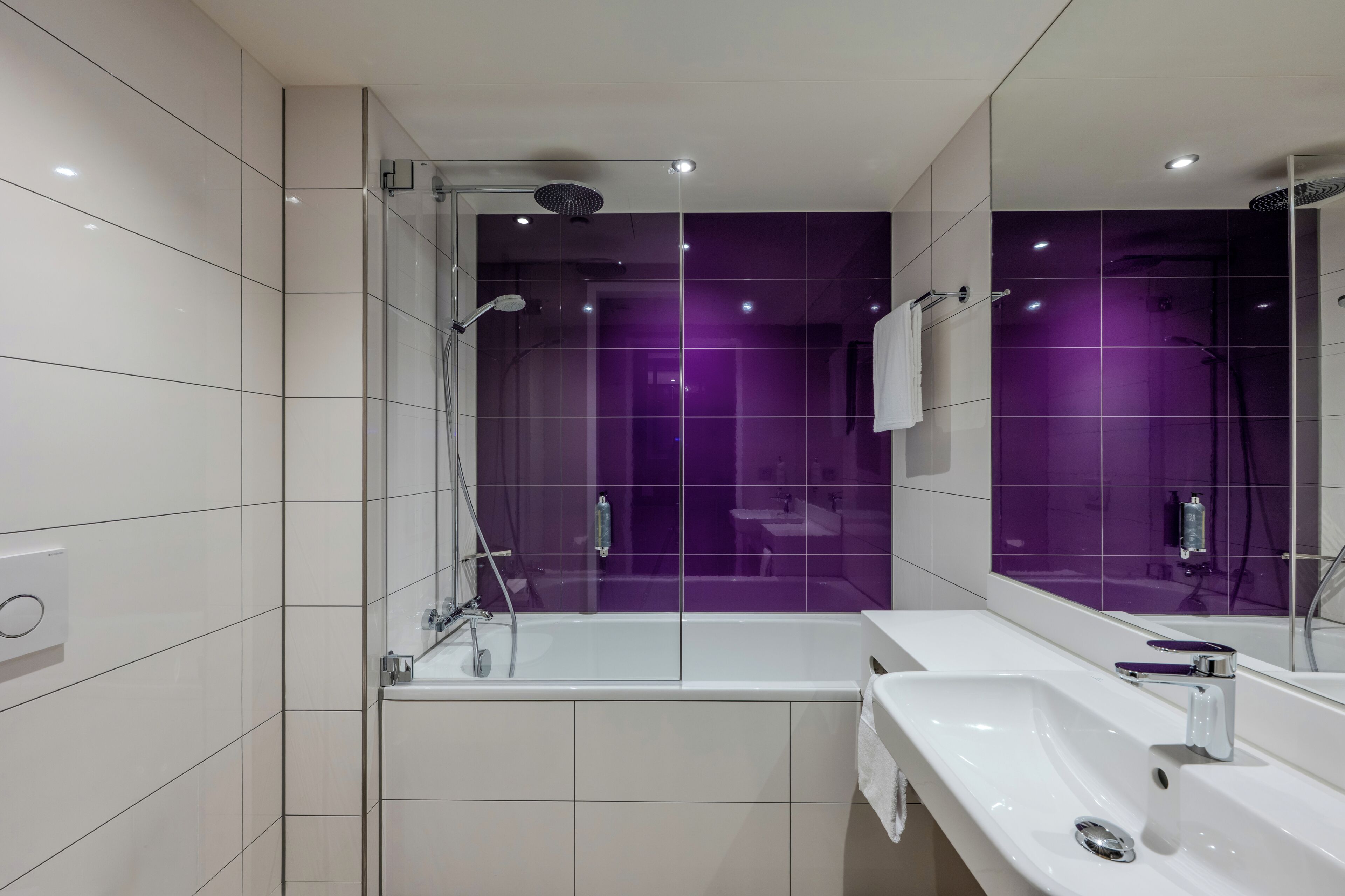A modern bathroom with a glass-enclosed shower, a white bathtub, and a white sink with a mirror.