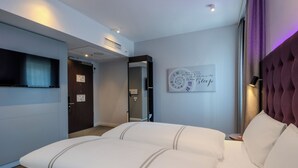 A hotel room with a large bed, a flat-screen TV, a mirror, a clock with a motivational quote, and a purple headboard. - Premier Inn Hannover City Centre (Hannover)