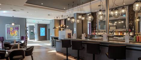 A modern bar area with a counter, bar stools, and hanging light fixtures.
