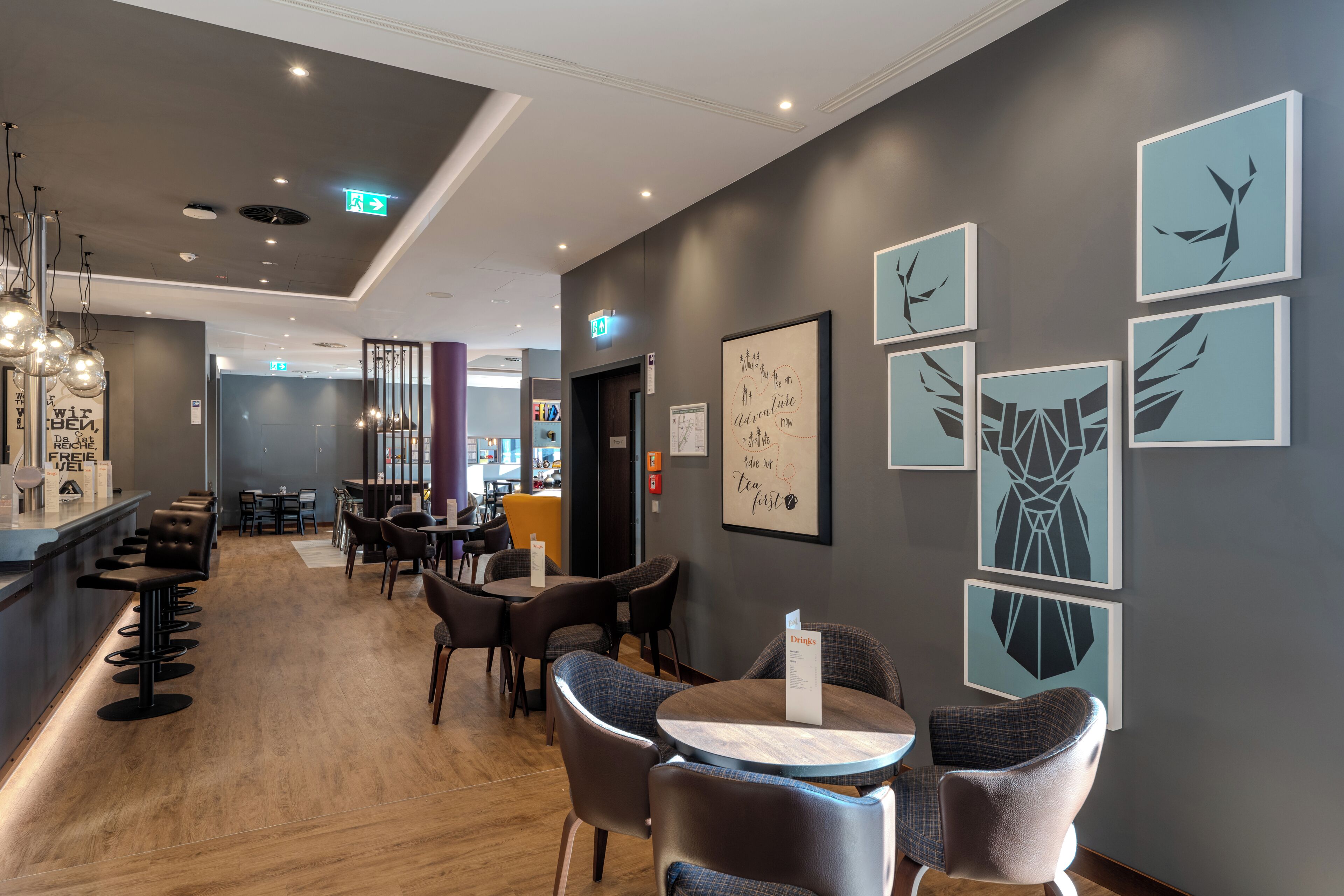 A modern hotel lobby with a bar area, seating arrangements, and wall art.