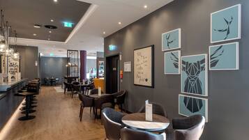 A modern hotel lobby with a bar area, seating arrangements, and wall art.