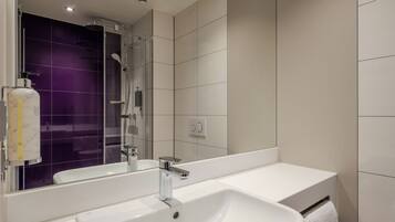 Un baño moderno con lavamanos blanco, espejo y zona de ducha.