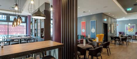 Un interior de restaurante moderno con mesas de madera, sillas de metal, iluminación colgante y un gran ventanal.