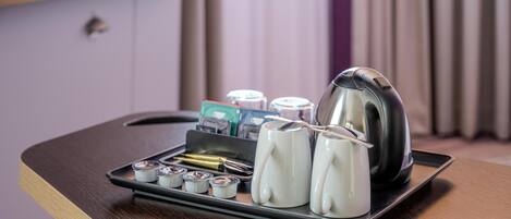 Una bandeja con una tetera, tazas y un portalápices con bolígrafo y libreta sobre una superficie de madera.