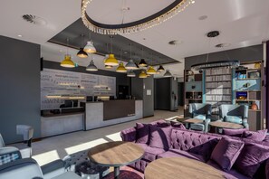 Un moderno vestíbulo de hotel con mostrador de recepción, zona de estar y una amplia estantería.