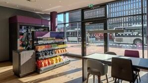 A modern interior with a vending machine, snack shelves, and a view of the street outside. - Premier Inn Hannover City Centre (Hannover)