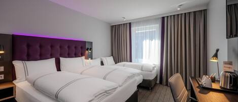 A hotel room with two beds, a desk with a lamp, a chair, a TV, and a sign indicating food and drinks.