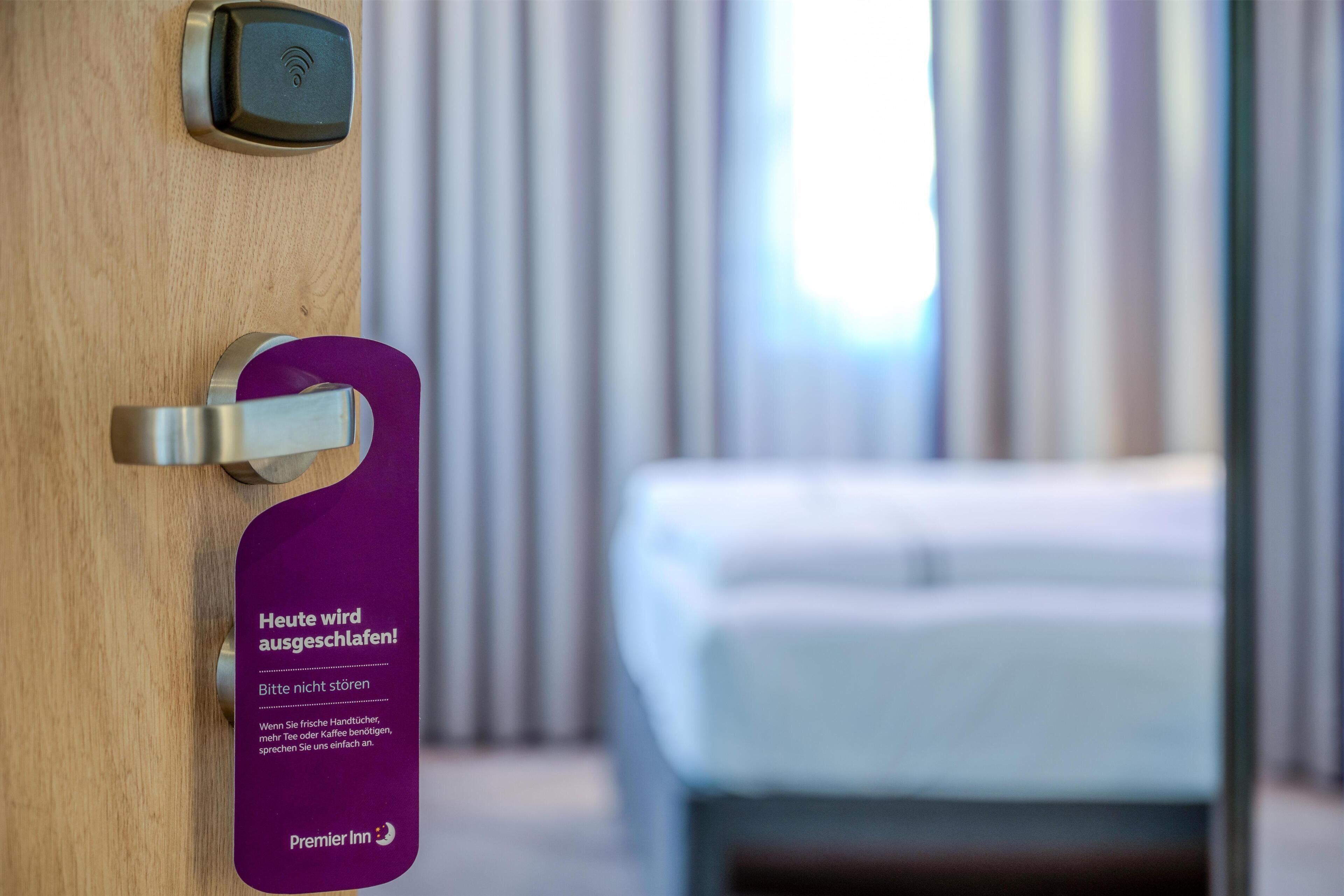 Puerta de una habitación de hotel con un cierre digital y un letrero púrpura que indica que la habitación está ocupada.