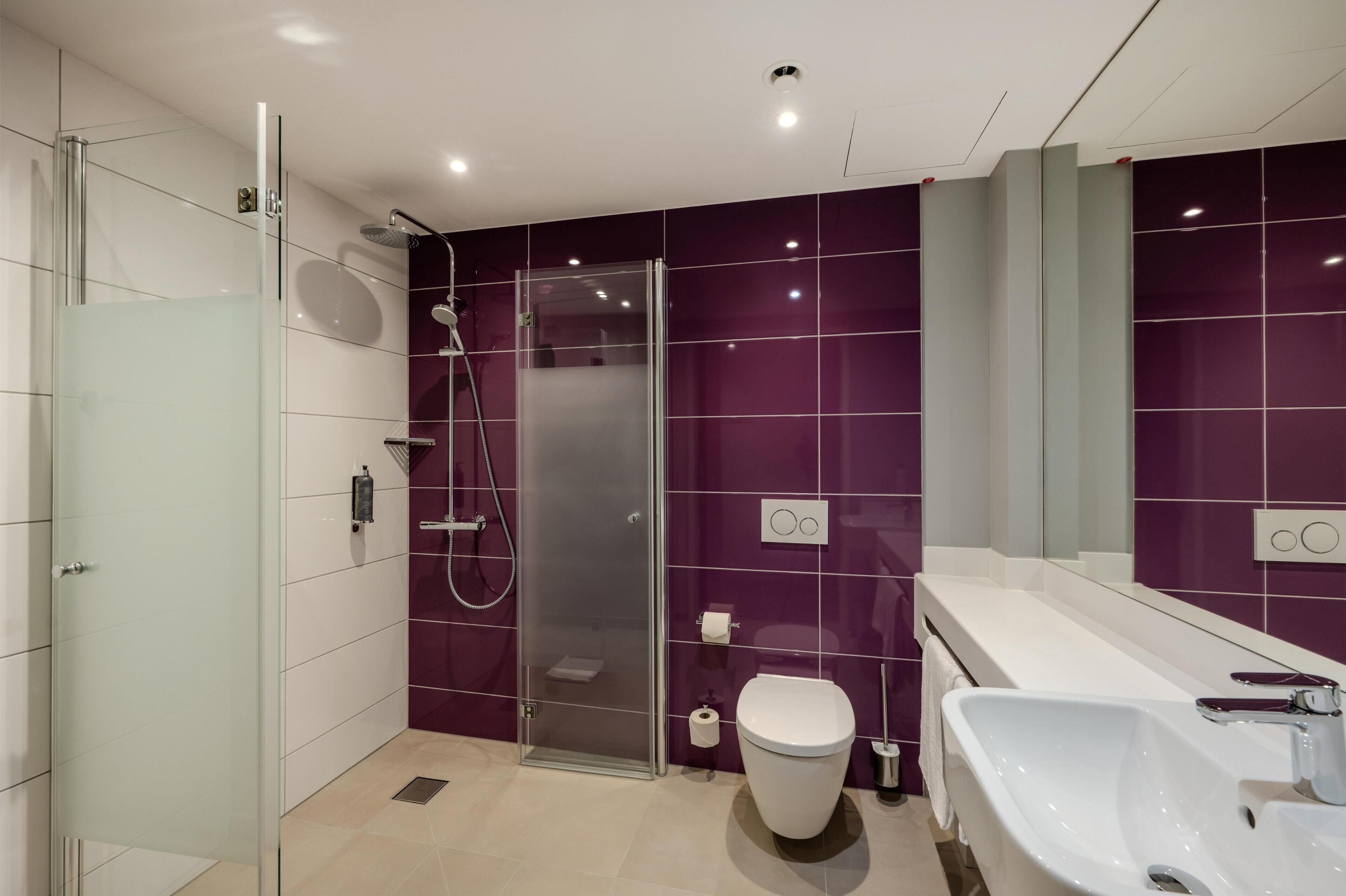 A modern bathroom with a glass shower enclosure, a white toilet, and a large sink.