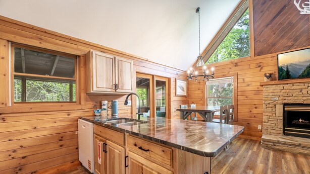 A wooden cabin interior with a kitchen, dining area, and fireplace. - Er39 2 Bedroom Cabin (Pigeon Forge)