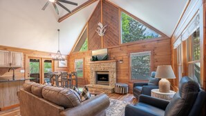 A log cabin interior with a fireplace, leather sofa, and dining area. - Er39 2 Bedroom Cabin (Pigeon Forge)