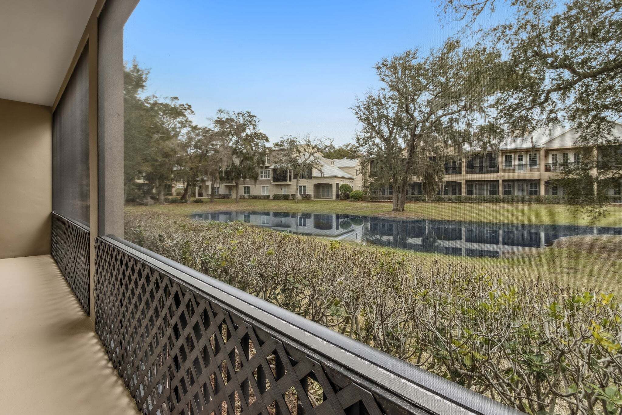 A balcony with a view of a courtyard, a pond, and a building with multiple windows and balconies.