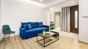 En moderne stue med en blå sofa, et glasbord og en grøn lænestol.