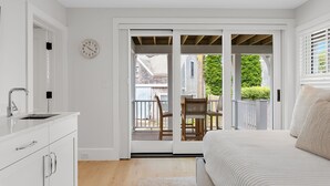 Un dormitorio con una cama, una mesita de noche, una ventana con persianas y vistas al exterior.