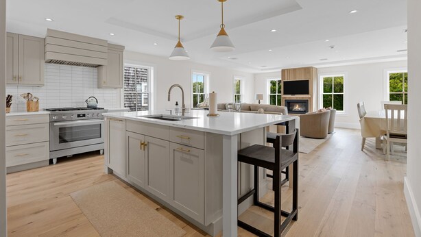 Una cocina moderna con armarios blancos, una isla central e iluminación colgante.