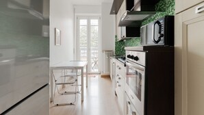 Una cocina moderna con refrigerador, estufa, microondas y un comedor con una silla y mesa.