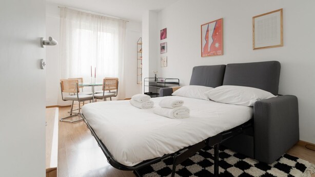 Un dormitorio moderno con cama, escritorio y silla.