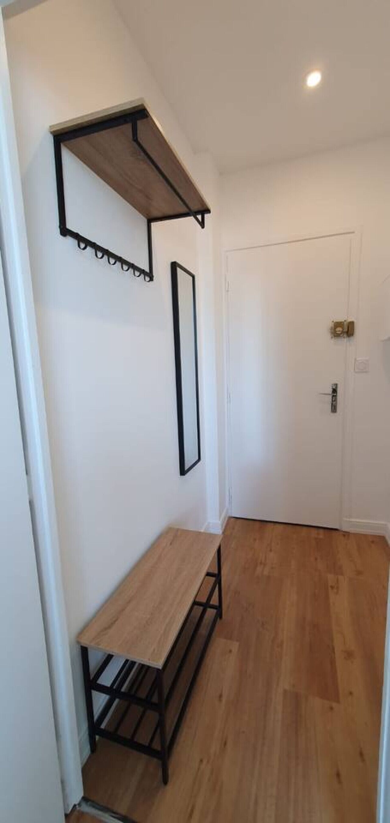 Ein Flur mit einer Holzbank, einem an der Wand befestigten Regal und einer Tür.