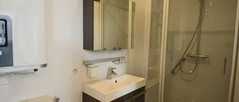 A modern bathroom with a glass-enclosed shower, a white sink, and a mirror above it.