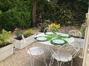 An outdoor dining area with a round table set for four, surrounded by white metal chairs. - Studio 15m², avec terrasse et place de parking (Aix-les-Bains)