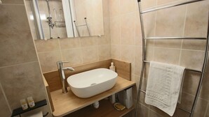 A bathroom with a white sink, a mirror, a towel rack, and a shower area.