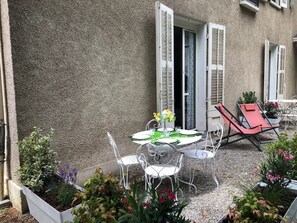 An outdoor patio with a round table, white chairs, and a red lounge chair. - Studio 15m², avec terrasse et place de parking (Aix-les-Bains)