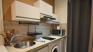 A compact kitchen with a sink, microwave, and washing machine.