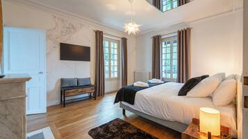 A bedroom with a bed, bedside lamp, and a view of the outdoors through windows.