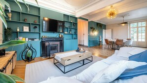 A modern living room with teal walls, a fireplace, a sofa, and a dining area.
