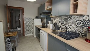 Una cocina compacta con encimera de madera, lavavajillas integrado y azulejos decorativos en la pared.