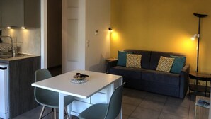 Espaço compacto com área de refeições, sofá e cozinha compacta.