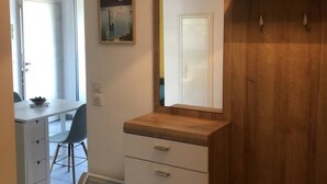 Quarto com guarda-roupa de madeira, uma escrivaninha com cadeira e radiador.