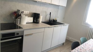 Eine kleine Küche mit Herd, Backofen, Spüle und Kaffeemaschine.