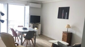 Ein modernes Wohnzimmer mit Essbereich, Fernseher und einem Gemälde an der Wand.