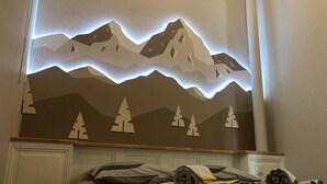 Una camera d'albergo con un letto, un'opera d'arte a tema montagna e un letto rifatto con coperta e cuscini.