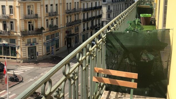 Un balcone con vista su una strada cittadina e montagne.