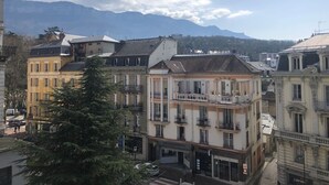 Un edificio a più piani con balconi, cielo sereno e montagne sullo sfondo.