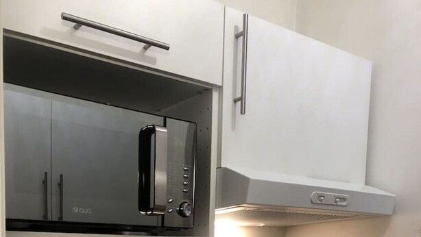 A modern kitchen with stainless steel appliances, including a microwave and oven, and a double sink. - Appartement T1 29 m², lumineux, Vue lac,  garage (Aix-les-Bains)