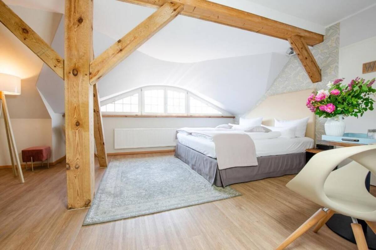 Ein Schlafzimmer mit schrägem Dach, einem Bett, einem Schreibtisch und einem Stuhl.
