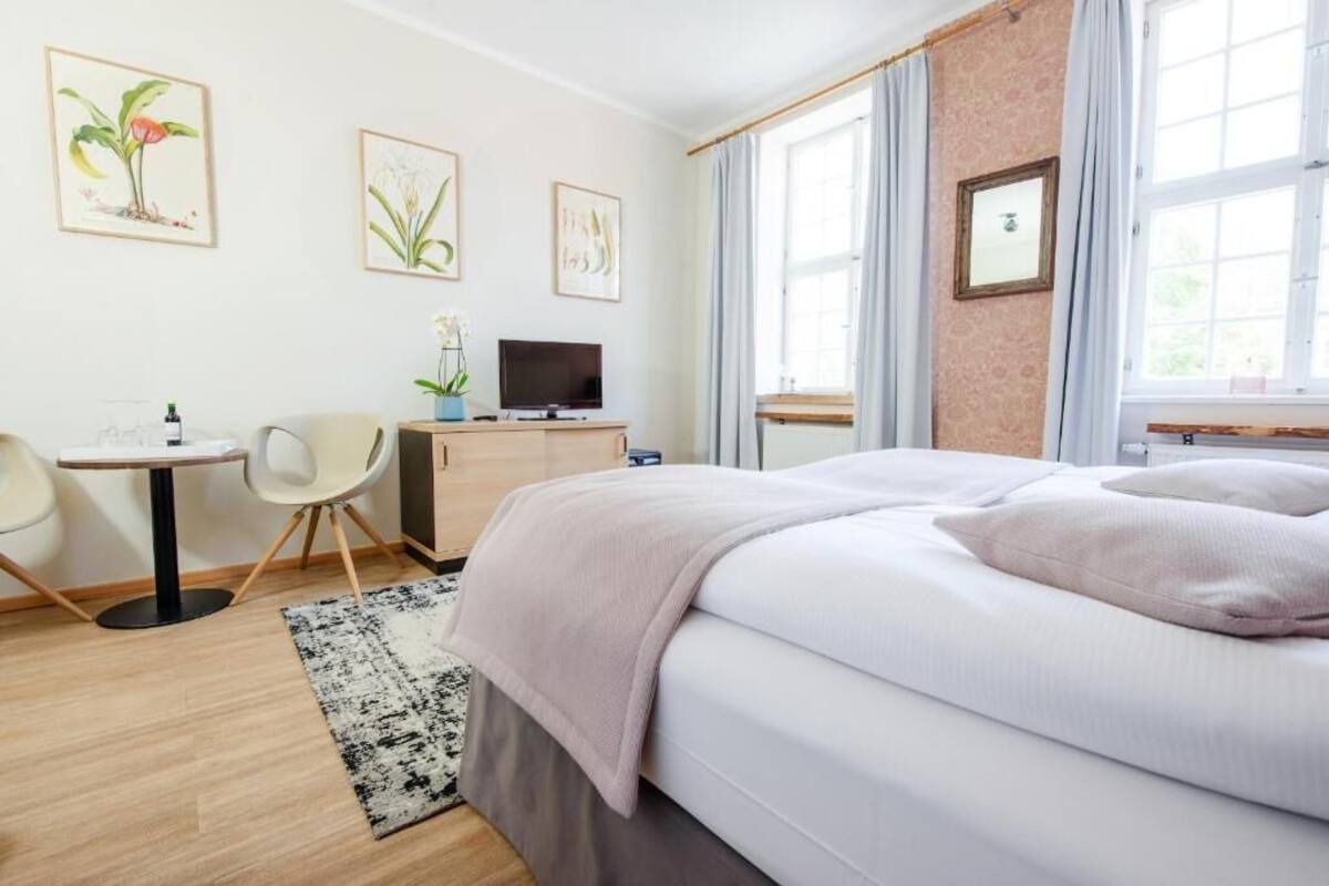 Ein Hotelzimmer mit Bett, Schreibtisch mit Stuhl, Fernseher und Bildern an den Wänden.