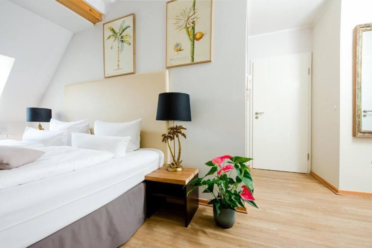 Ein Schlafzimmer mit Bett, Nachttischen, einer Lampe und einem Blumentopf.
